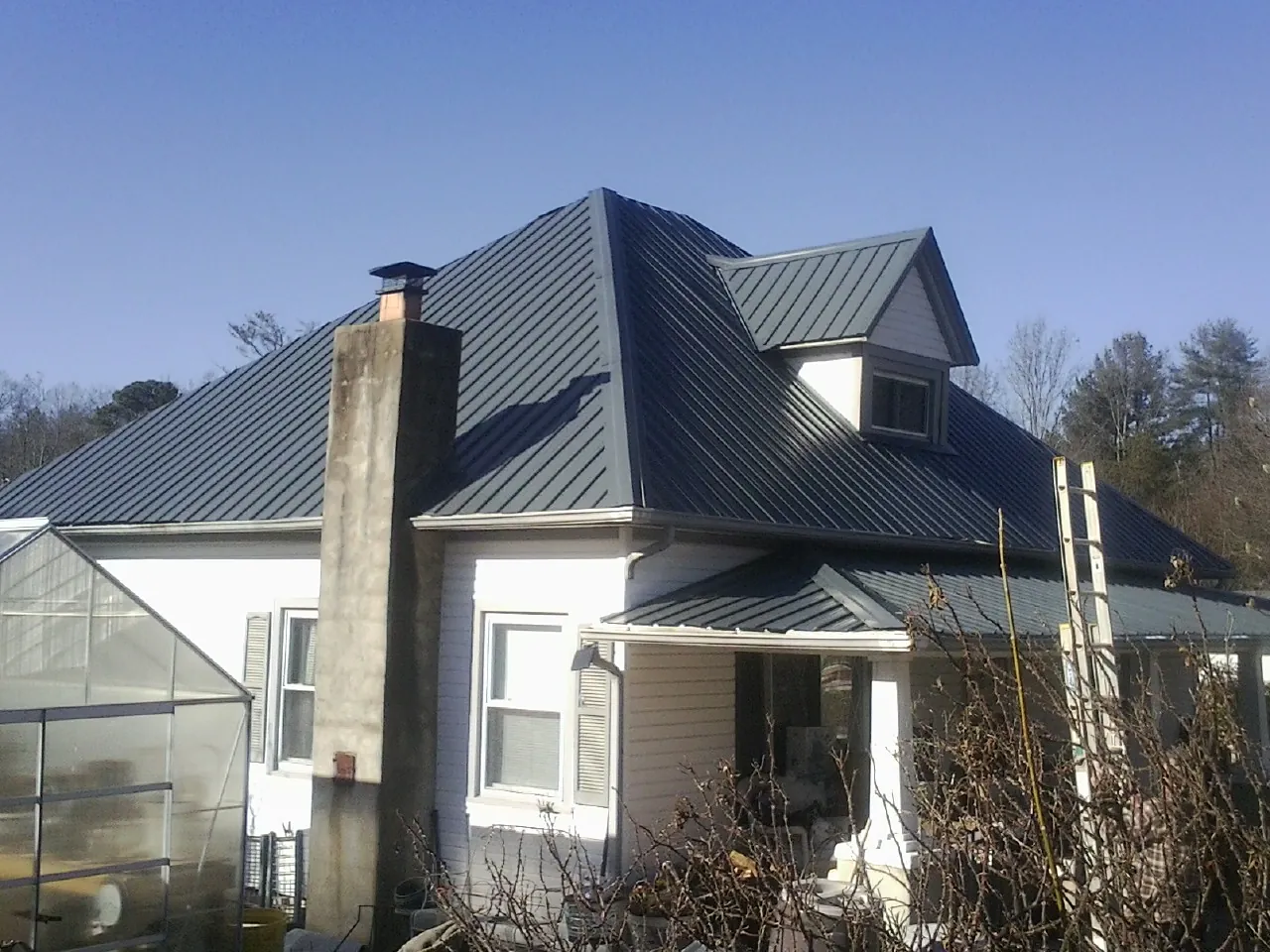 Dark blue standing seam metal roof on a white farmhouse with dormer — Slate & Tile Roof Repair by Roofing Brothers in Mentor