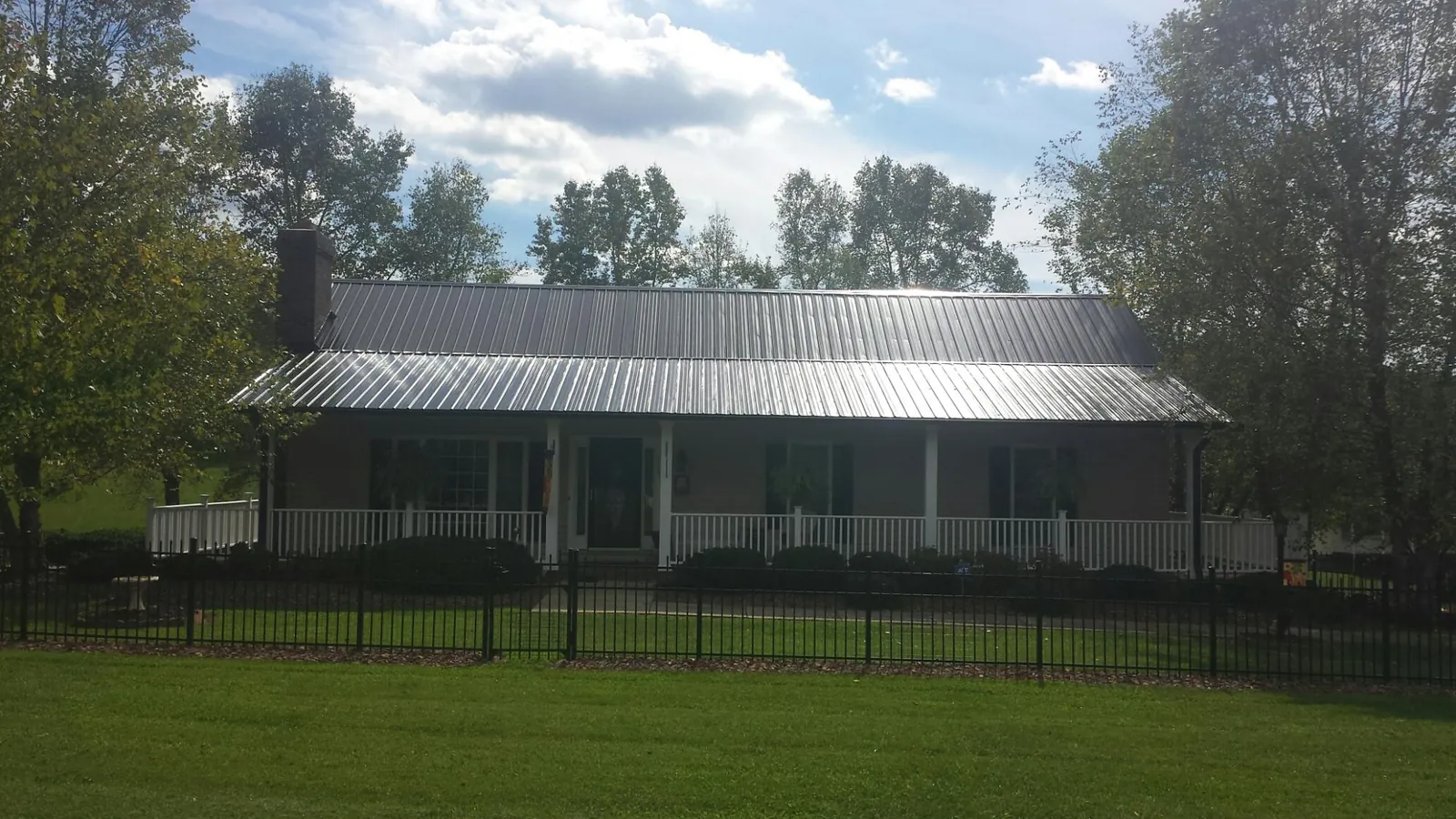 Gray metal roof on a brick ranch with a full width front porch — Gutter Guard Installation work by our crew in Mentor