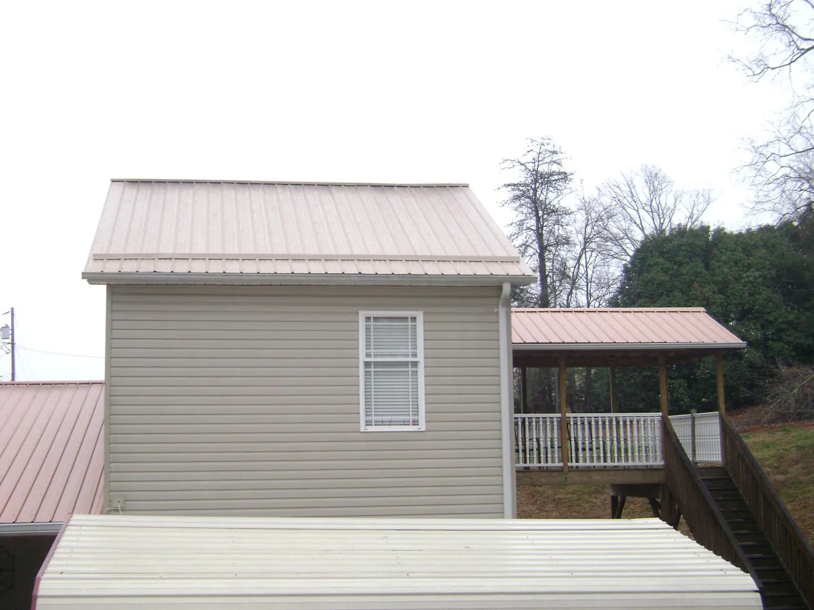 Tan metal roofs on a two story addition and attached porch, from a Roof Replacement job in Mentor